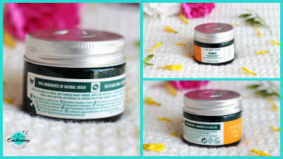 A collage featuring three images of The Body Shop Vitamin C Glow Boosting Moisturiser. The main left image shows the back of the dark green glass jar, detailing ingredients and product information. The top right image is a top-down view of the closed jar. The bottom right image shows the front of the jar with its orange and white label. All images are set against a soft white background with scattered yellow flower petals and blurred pink flowers.