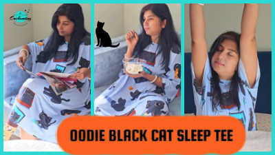 A multi-panel image showcasing uk lifestyle blogger Anamika Chattopadhyaya lounging and relaxing in the Oodie Black Cat Sleep Tee. She is shown reading a magazine in the left panel and eating a snack in the center panel, which also features a silhouette of a black cat. The right panel shows her stretching comfortably in bed with her arms raised, emphasizing the tee's roomy, oversized fit and its use as comfortable loungewear. A large orange text bubble overlay reads "OODIE BLACK CAT SLEEP TEE".