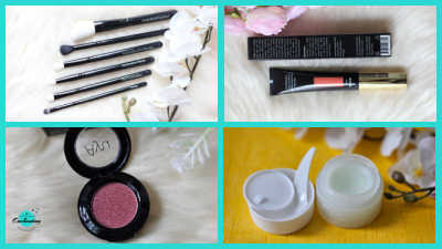 A four-panel collage featuring a beauty haul from Ayu Cosmetics. The top-left panel shows a set of five black makeup brushes next to white flowers. The top-right shows a tube of liquid makeup and its black packaging. The bottom-left features an open round pot of shimmering berry-pink eyeshadow with "Ayu" printed on the lid. The bottom-right displays a white jar of skincare cream with a small application spatula.