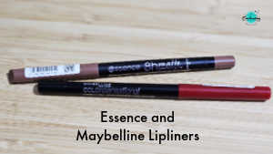 Two lipliner pencils lying horizontally on a light wood surface. The top pencil is an Essence 8h Matte comfort lipliner in a nude brown shade. The bottom pencil is a Maybelline Color Sensational lipliner in a bold red shade. Text at the bottom of the image reads "Essence and Maybelline Lipliners."