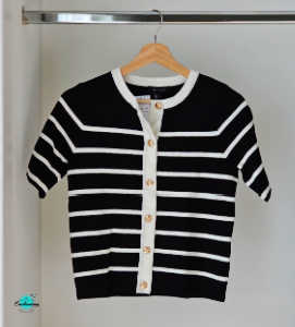 A black and white striped, short-sleeved knit cardigan from New Look hanging on a wooden hanger. The top features a white crew neckline, a white vertical button placket, and several round gold buttons down the front.