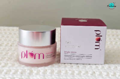 A frosted glass jar of Plum Bright Years Restorative Overnight Crème with a silver cap resting beside its matching white and maroon packaging box on a textured white surface, with the Everything Enchanting logo in the top-right corner.